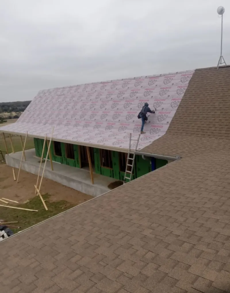Worker preparing underlayment for a metal roof installation in Moline